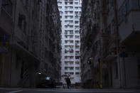 <p>A man walks in front of a residential and commercial building, center, where the “coffin home” are located in Hong Kong. (Photo: Kin Cheung/AP) </p>