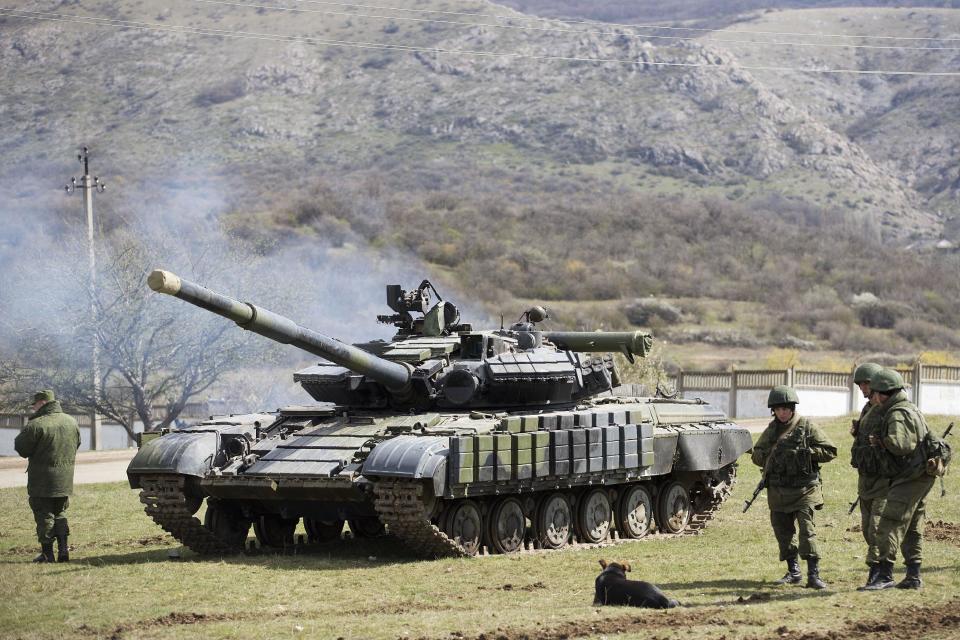 Russian soldiers stand near a tank at a former Ukrainian military base in Perevalne, outside Simferopol, Crimea, March 27, 2014. Russia last week completed the annexation of Crimea following a referendum in which an overwhelming number of residents voted to break off from Ukraine and join Russia. The vote, rejected by Ukraine and the West, was hastily called after Russian forces had overtaken the peninsula. (AP Photo/Pavel Golovkin)