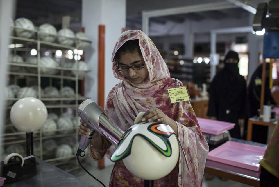 An employee uses hot air as she sticks outer panels on a soccer ball inside the soccer ball factory that produces official match balls for the 2014 World Cup in Brazil, in Sialkot, Punjab province