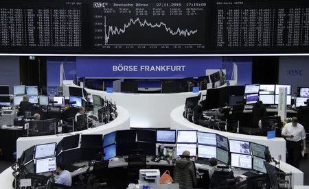 Traders are pictured at their desks in front of the DAX board at the stock exchange in Frankfurt, Germany, November 27, 2015. REUTERS/Staff/Remote