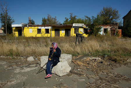 A woman sits in front of the damaged building of a store near the airport in Donetsk, Ukraine, September 26, 2017. REUTERS/Alexander Ermochenko