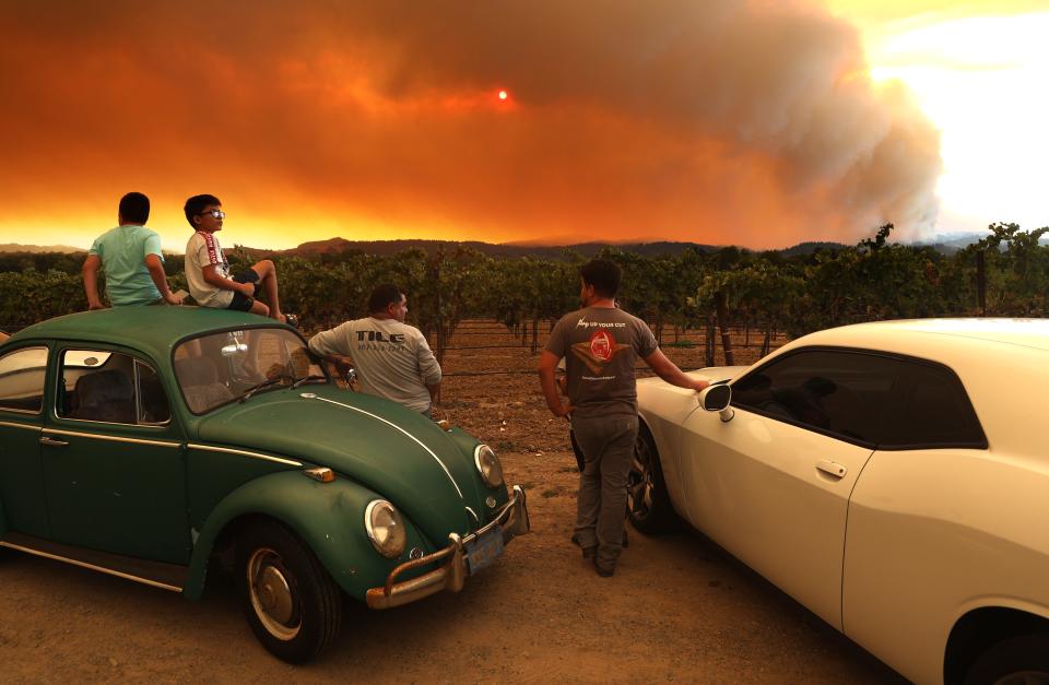 Residents sit next to a vineyard as they watch the LNU Lightning Complex Fire burn in nearby hills on Aug. 20 in Healdsburg, Calif.