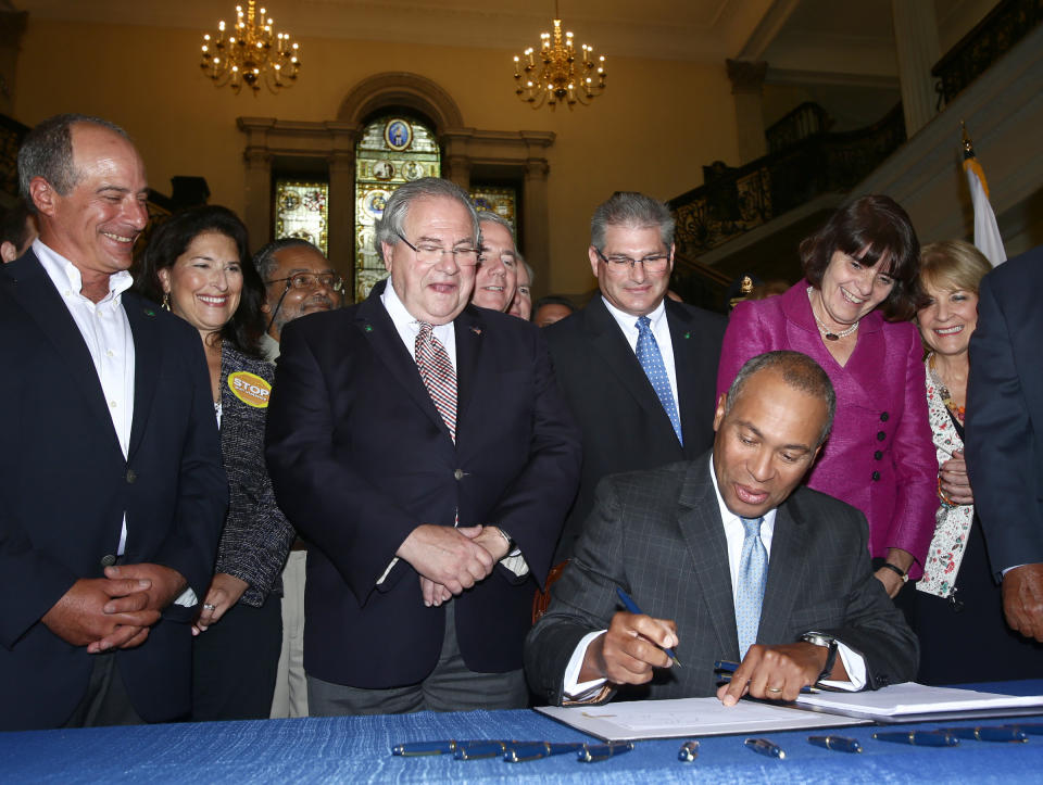 Deval Patrick, former governor of Massachusetts, signs a 2014 gun violence bill while Robert DeLeo, the House Speaker, looks on. That measure&nbsp;made the state's laws, already among&nbsp;nation's strongest, even stronger. (Photo: Boston Globe via Getty Images)