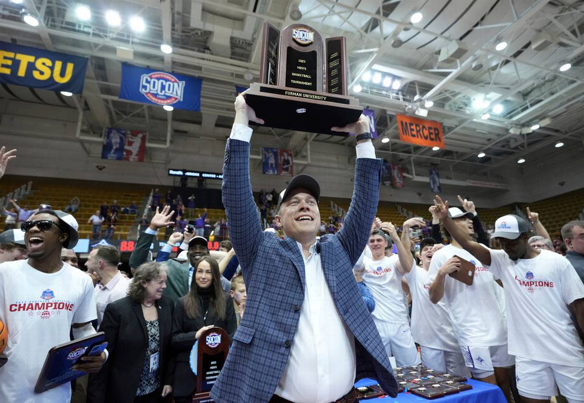 Furman head coach Bob Richey hoists the Southern Conference Championship trophy in the air after Furman defeated Chattanooga in the NCAA men’s college basketball championship game for the Southern Conference tournament, Monday, March 6, 2023, in Asheville, N.C.