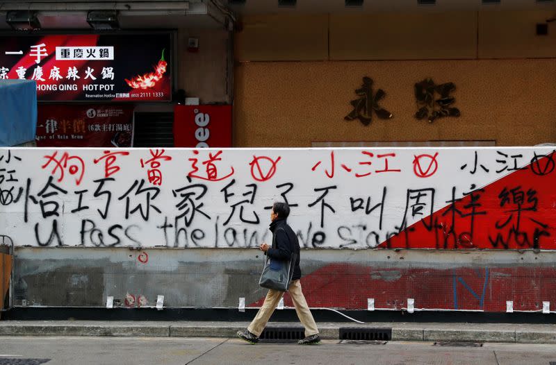 A man walks past graffiti sprayed by protesters on a wall in Hong Kong