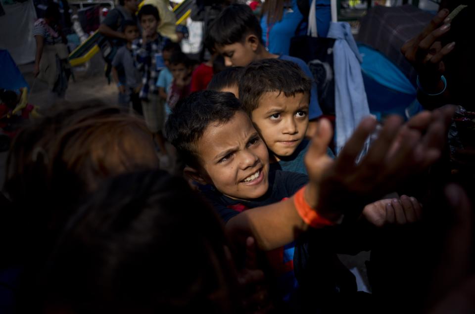 Children, part of the migrant caravan, ask for sweets at a shelter in Tijuana, Mexico, Wednesday, Nov. 21, 2018. Migrants camped in Tijuana after traveling in a caravan to reach the U.S are weighing their options after a U.S. court blocked President Donald Trump's asylum ban for illegal border crossers. (AP Photo/Ramon Espinosa)