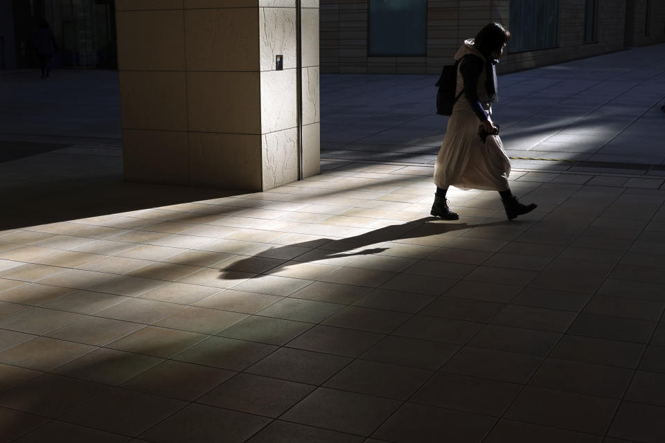 A woman wearing a protective mask to help curb the spread of the coronavirus walks in Tokyo, Thursday, Dec. 17, 2020. The Japanese capital confirmed more than 800 new coronavirus cases on Thursday. (AP Photo/Eugene Hoshiko)