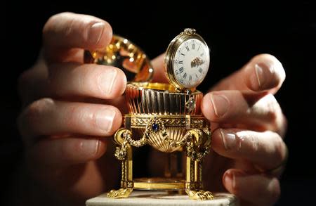 An assistant poses for a photograph with a Faberge egg during a photo-call at antique dealer Wartski, in central London April 7, 2014. REUTERS/Olivia Harris