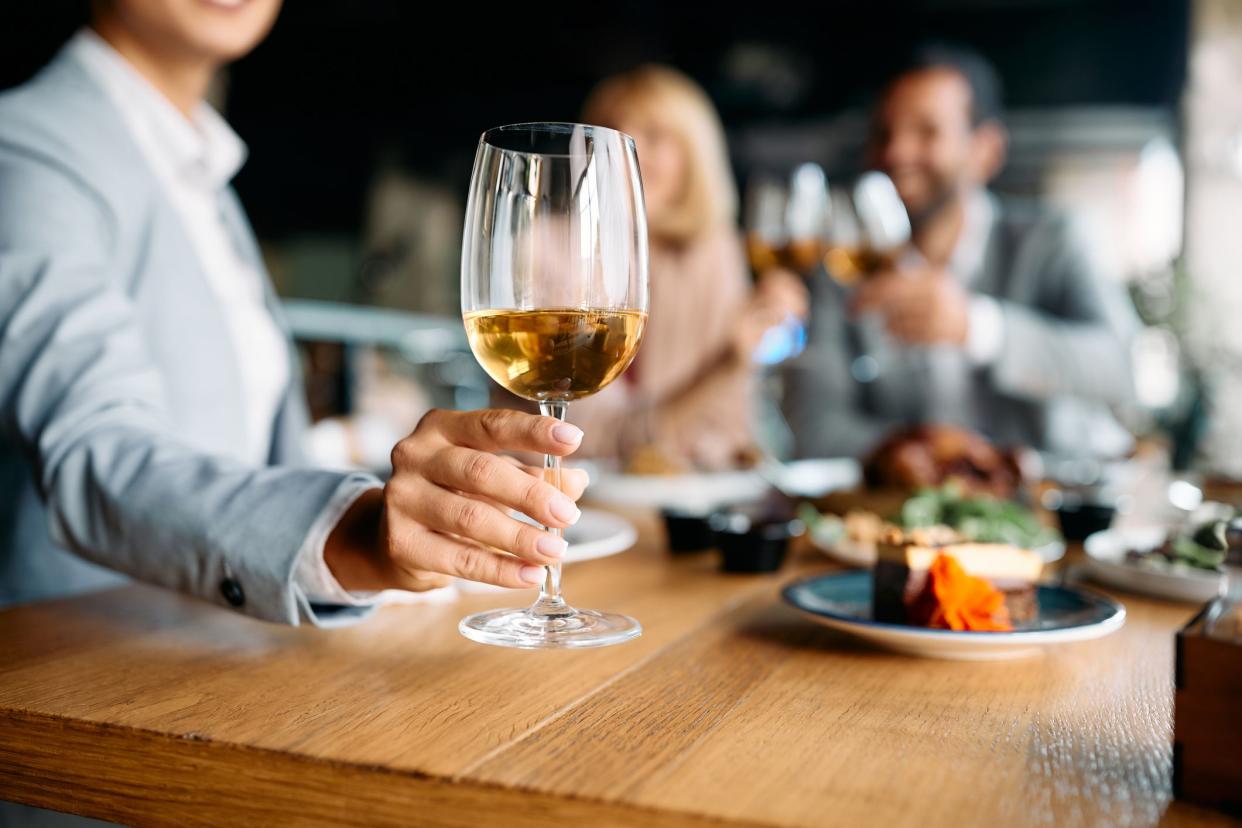 Close up of businesswoman having a glass of wine during lunch in restaurant.