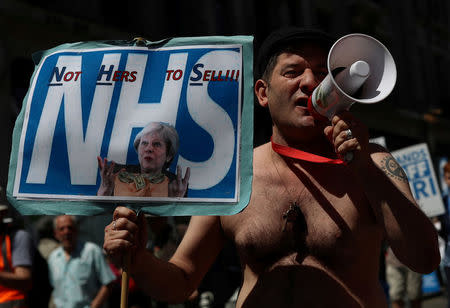 Demonstrators hold placards during a march in support of the National Health Service, in central London, Britain, June 30, 2018. REUTERS/Simon Dawson/Files