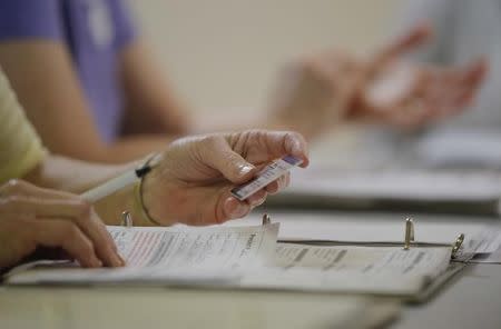 An election worker checks a voter's drivers license as North Carolina's controversial "Voter ID" law goes into effect for the state's presidential primary election at a polling place in Charlotte, North Carolina, U.S. on March 15, 2016. REUTERS/Chris Keane/File Photo