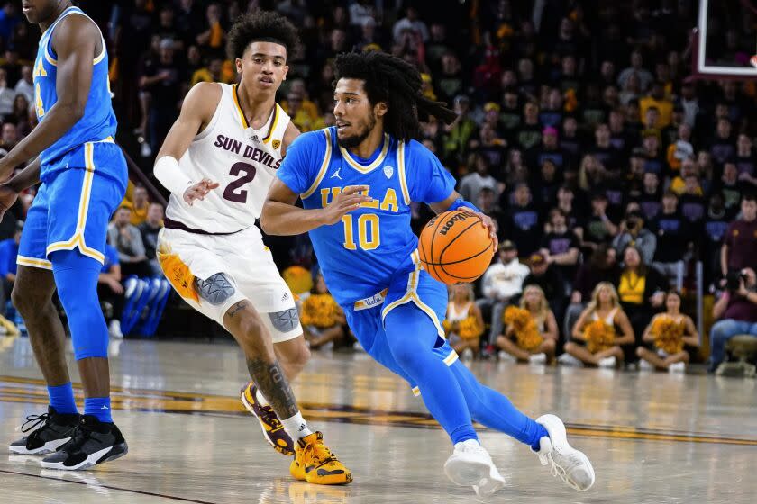 UCLA's Tiger Campbell (10) drives around Austin Nunez, Ariz. (2) during the first half of an NCAA college basketball game, Thursday, Jan. 19, 2023, in Tempe, Ariz. (AP Photo/Darryl Webb)
