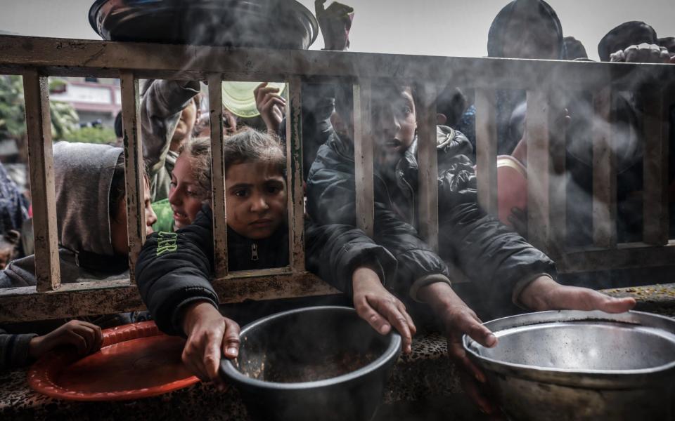 Displaced Palestinian children gather to receive food at a government school in Rafah