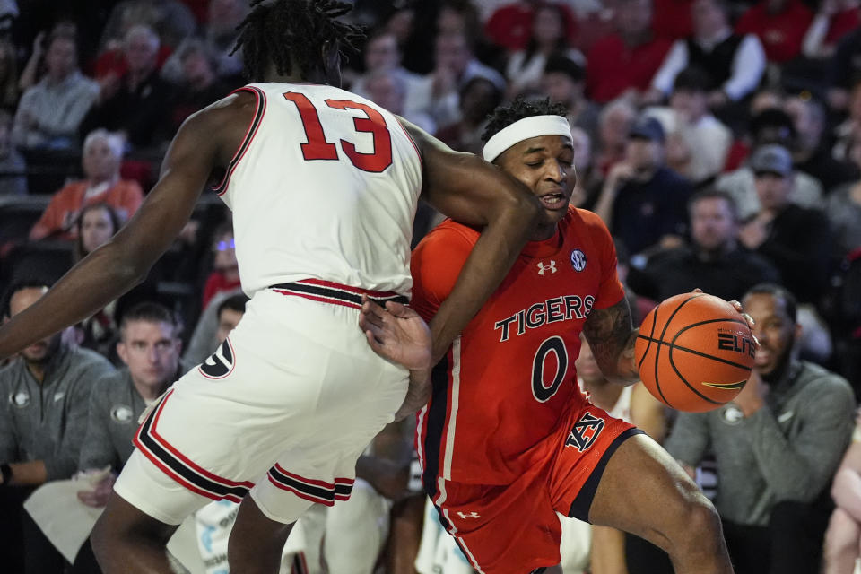 Auburn guard K.D. Johnson (0) is fouled as he tries to get around Georgia forward Dylan James (13) during the first half of an NCAA college basketball game Saturday, Feb. 24, 2024, in Athens, Ga. (AP Photo/John Bazemore)