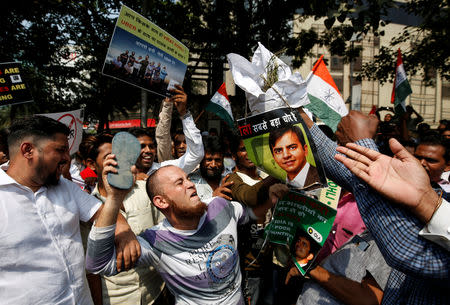 A man hits a poster of Bhavish Aggarwal, CEO and co-founder of Ola, with a slipper during a protest against Ola and Uber outside Uber's head office in Mumbai, India, October 22, 2018. REUTERS/Francis Mascarenhas