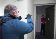 The Rev. April Keech, an Anglican priest, who organizes food deliveries to old and vulnerable people, gestures after dropping off food to a woman in London, Saturday, March 28, 2020. Keech and her team of volunteers have spent the past two weeks buying groceries, filling prescriptions and making deliveries to residents in east London who are at risk of serious illness or death from the COVID-19 disease. The new coronavirus causes mild or moderate symptoms for most people, but for some, especially older adults and people with existing health problems, it can cause more severe illness or death. (AP Photo/Alberto Pezzali)