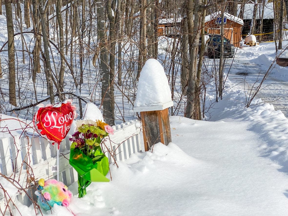 Flowers and a balloon sit outside 25 Maple St. in Eganville, Ont., where police were called on Jan. 25 and found the body of Lisa Sharpe.  (Stu Mills/CBC - image credit)