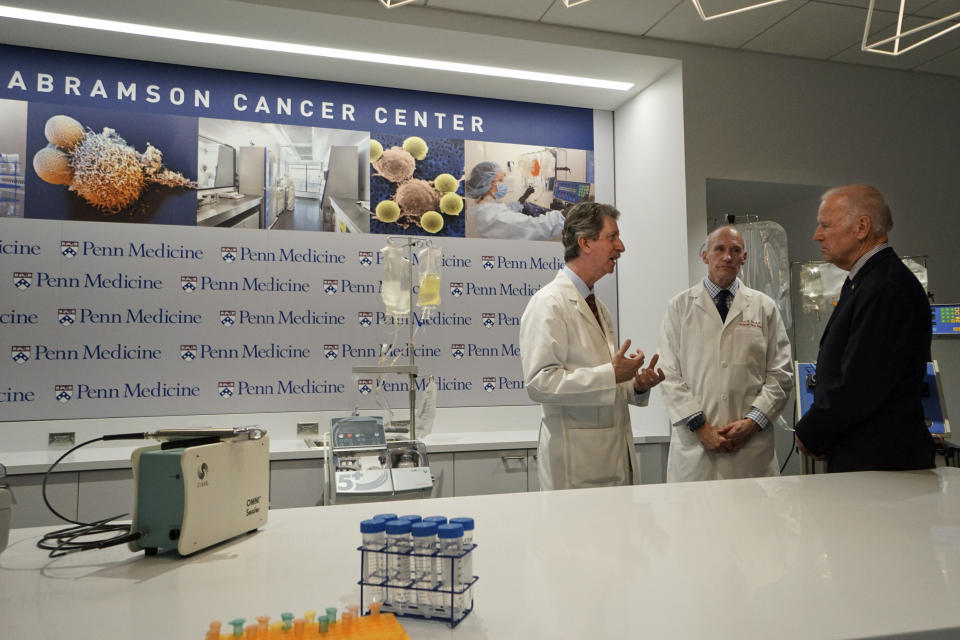 FILE - In this Jan. 15, 2016 file photo, Vice President Joe Biden listens to Dr. Bruce L. Levine PH.D., left, and Dr. Carl H. June M.D., center, in the Abramson Cancer Center at the University of Pennsylvania in Philadelphia. Biden’s defining venture since leaving the Obama White House is the Biden Cancer Initiative, a nonprofit aimed at speeding a cancer cure in memory of his son. (AP Photo/ Joseph Kaczmarek, Pool)