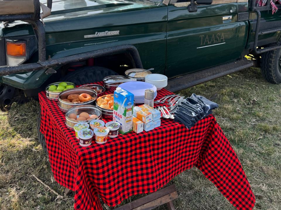 Tassa Lodge safari breakfast on plaid tablecloth next to a truck 