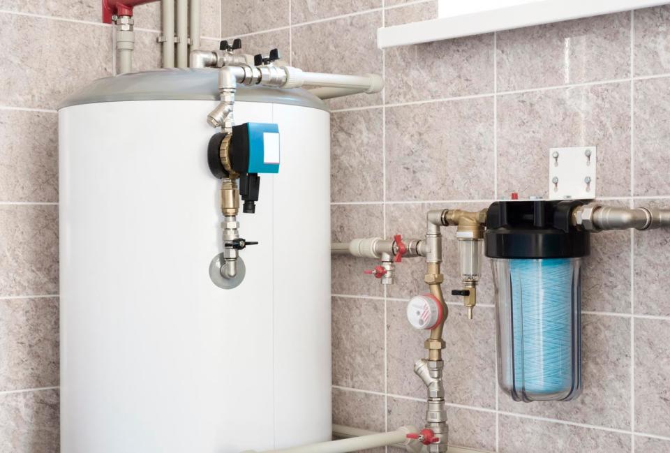 A white water heater is the focus in a tiled room.