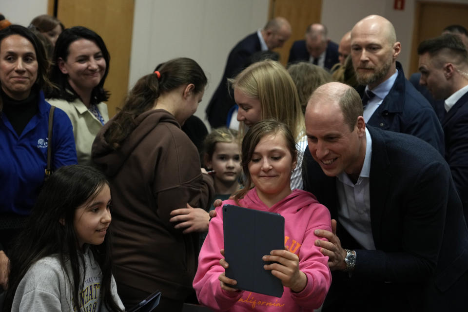 Britain's Prince William takes a photo with children as he visits an accommodation centre, for Ukrainians who fled the war, in Warsaw, Poland, Wednesday, March 22, 2023. (AP Photo/Czarek Sokolowski)