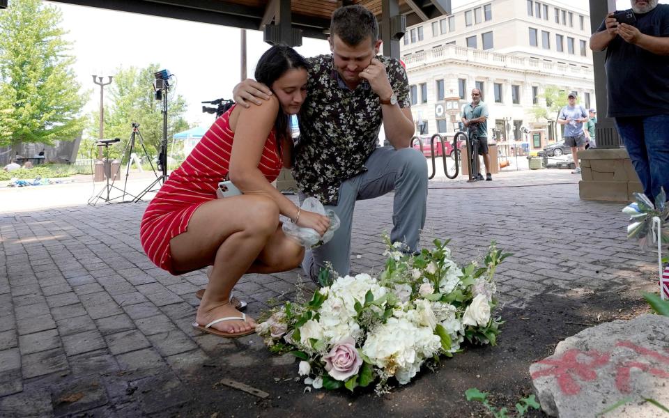 Passers-by pay tributes to the victims of the Highland Park shooting in Chicago on Monday, during the independence day parade - Charles Rex Arbogast/AP