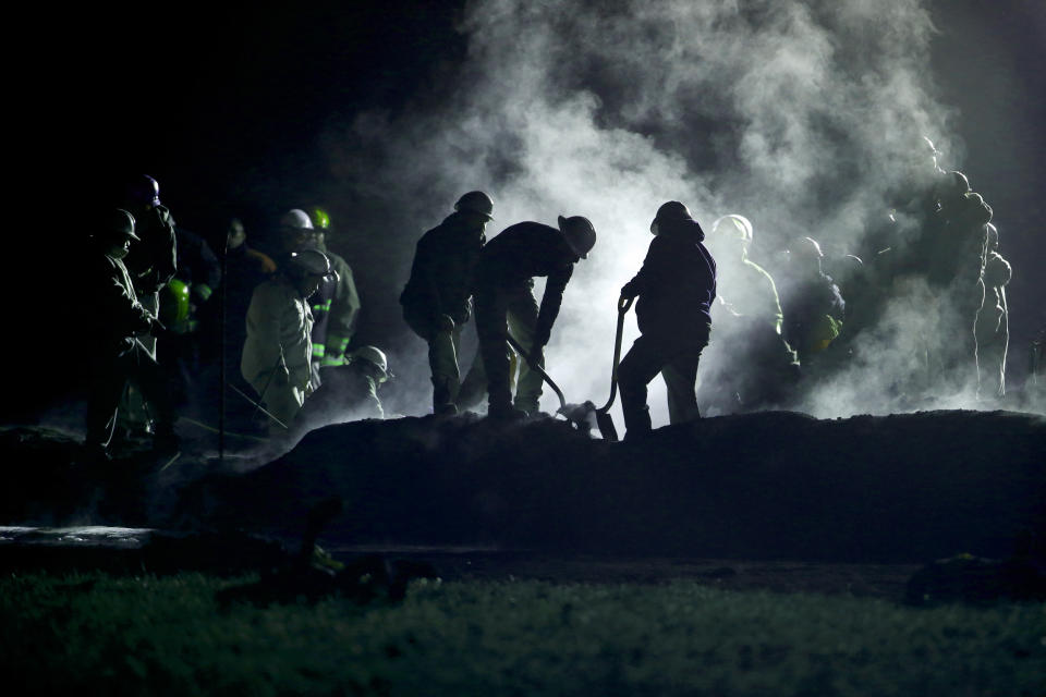 Staff of Pemex, Petroleos Mexicanos, works the area of a oil pipeline explosion in Tlahuelilpan, Hidalgo state, Mexico, Saturday, Jan. 19, 2019. A massive fireball that engulfed people scooping up fuel spilling from a pipeline ruptured by thieves in central Mexico killed several people and badly burned others. (AP Photo/Claudio Cruz)