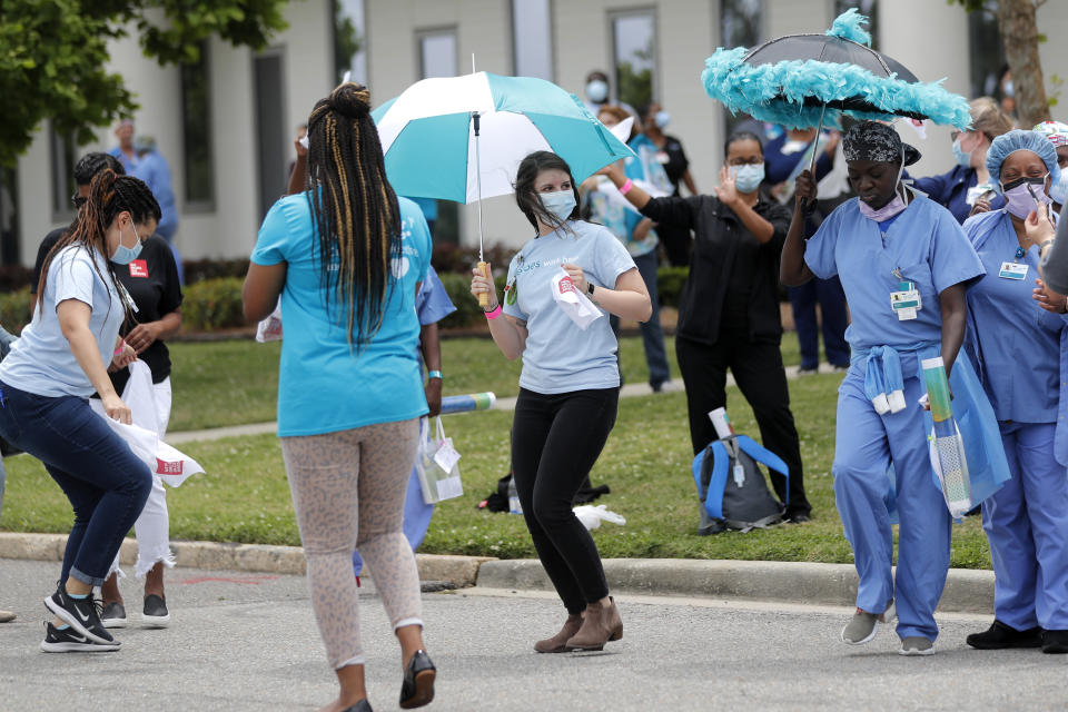 Healthcare workers at New Orleans East Hospital wave handkerchiefs and dance to a jazz serenade, as a tribute for their care of COVID-19 patients, by the New Orleans Jazz Orchestra, outside the hospital in New Orleans, Friday, May 15, 2020. A New York woman collaborated with the New Orleans Jazz Orchestra to put on what she calls a stimulus serenade to give moral support to front-line hospital workers and COVID-19 patients in New Orleans (AP Photo/Gerald Herbert)