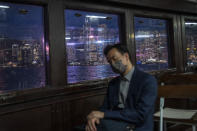 FILE - The city skyline is seen as a man naps on the Star Ferry in Hong Kong, on Oct. 19, 2022. The exodus of tens of thousands of professionals from Hong Kong triggered by Beijing's crackdown on its civil liberties is being offset by new arrivals: mainland Chinese keen to move to the former British colony. (AP Photo/Vernon Yuen, File)