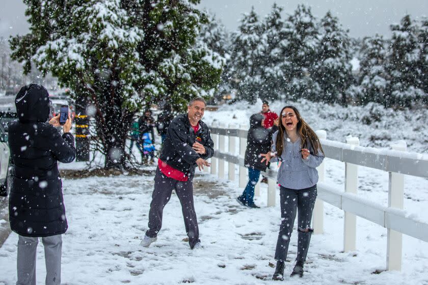 Rancho Cucamonga, CA - February 25: Sandi Nelson, left, photographs as her husband Tim Nelson and 18-year-old daughter Sarah Nelson play in freshly fallen snow on top of Haven Avenue on Saturday, Feb. 25, 2023 in Rancho Cucamonga, CA. (Irfan Khan / Los Angeles Times)