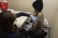 In this Dec. 18, 2020, photo provided by the Oregon Health & Science University, Danielle Salinas, a frontline employee who works at OHSU's drive-through COVID-19 testing site at Hillsboro Stadium, receives a Pfizer BioNtech COVID-19 vaccine injection in Hillsboro, Ore. As America's mass vaccination campaign gets underway and the virus surges, the nation is facing a moral dilemma as officials from California to New Jersey decide who gets the vaccine first. (Josh Andersen/OHSU via AP)