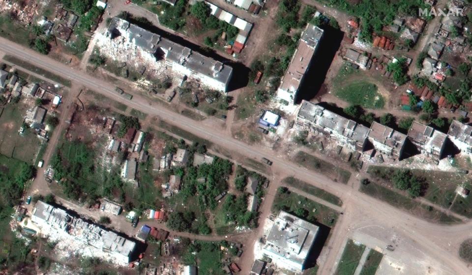 Una unidad rusa desplegada a lo largo de un camino y las consecuencias de los bombardeos con artilleria con edificios destruidos, en Popasna, un pueblo cerca de la ciudad de Sievierodonetsk (Maxat Technologies/AP)