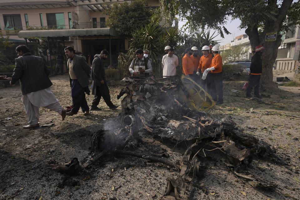 Security officials examine the wreckage of a car at the site of bomb explosion, in Islamabad, Pakistan, Friday, Dec. 23, 2022. A powerful car bomb detonated near a residential area in the capital Islamabad on Friday, killing some people, police said, raising fears that militants have a presence in one of the country's safest cities. (AP Photo/Anjum Naveed)