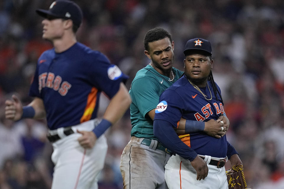 Seattle Mariners' Julio Rodriguez, center, pushes Houston Astros starting pitcher Framber Valdez, right, away from home plate after he hit Mariners' Jose Caballero, causing the benches to clear during the fifth inning of a baseball game, Saturday, Aug. 19, 2023, in Houston. (AP Photo/Kevin M. Cox)