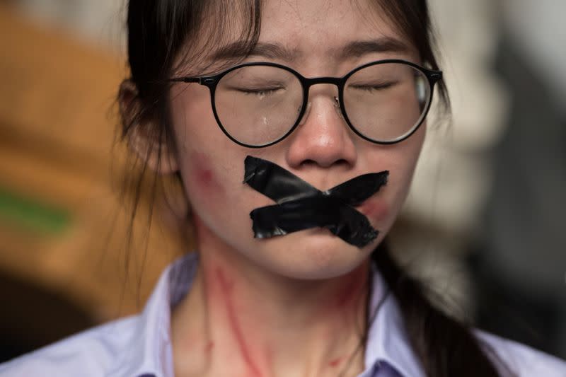 Nalinrat Tuthubthim, 20, a student, who claims she was sexually abused by a teacher, has her mouth covered with tape during a rally in Bangkok