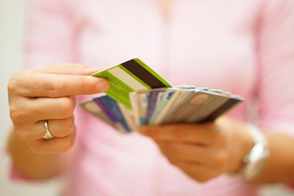 A person pulls a credit card out from a fanned-out stack of cards in her hands.