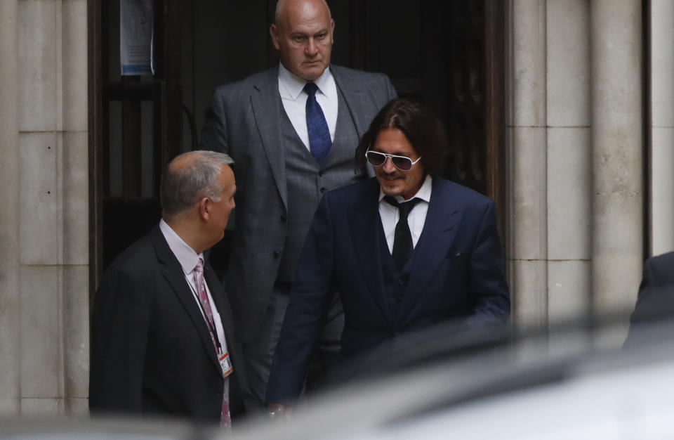 El actor Johnny Depp, a la derecha, sale del Alto Tribunal en Londres el martes 7 de julio de 2020. El caso de difamación de Depp contra un tabloide británico por un artículo de 2018 en el que se afirmó que era violento con su exesposa Amber Heard comenzó el martes. Depp niega vehementemente los señalamientos. (AP Foto/Alastair Grant)