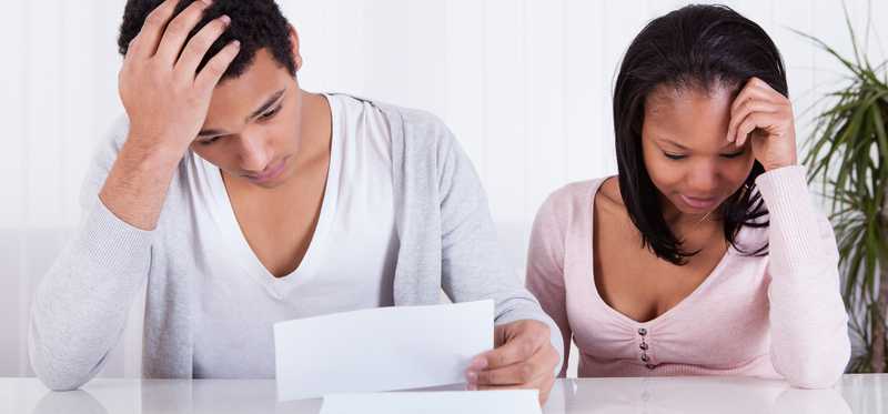 A worried couple looks at paperwork.