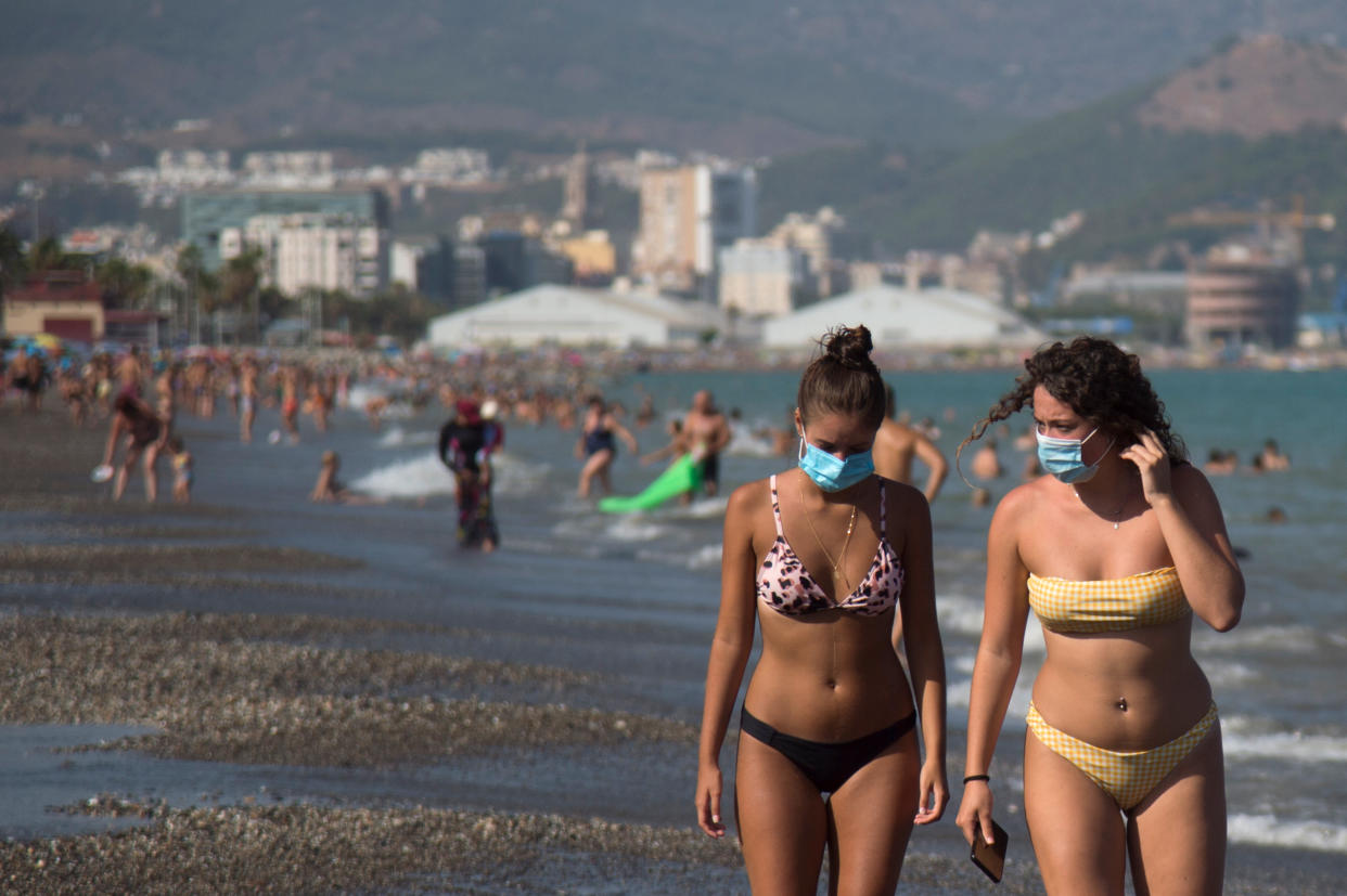 Women wearing face masks walk along La Misericordia Beach in Malaga on July 22. (Getty)