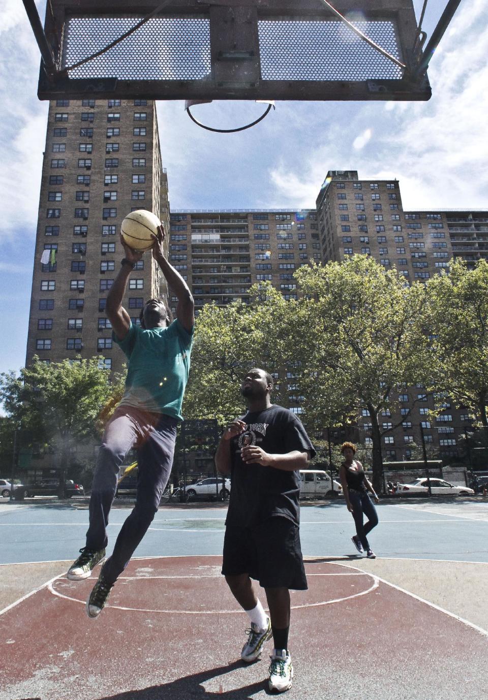 Eric Johnson, left, 19, and Mario Volcin, 23, play basketball in the Jackie Robinson Playground as the Ebbets Field apartments looms in the background, on Wednesday, Sept. 19, 2012 in Brooklyn, N.Y. Ebbets Field, home to the Brooklyn Dodgers baseball decades ago, became a sprawling residential complex to thousands after the Dodgers moved west. Now Brooklyn is hitting the major leagues again with a new arena and the Brooklyn Nets' NBA franchise. (AP Photo/Bebeto Matthews)