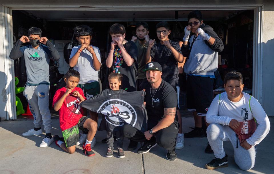 Rigo Avila, founder of A.V.I.L.A Victory Boxing is photographed with some of his students after a training session outside Avila's parent's home garage in Greenfield on May 4.