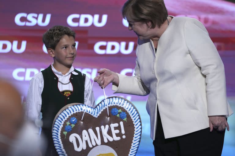 Un chico bávaro le entrega un regalo de agradecimiento a la canciller Angela Merkel por su gestión de gobierno