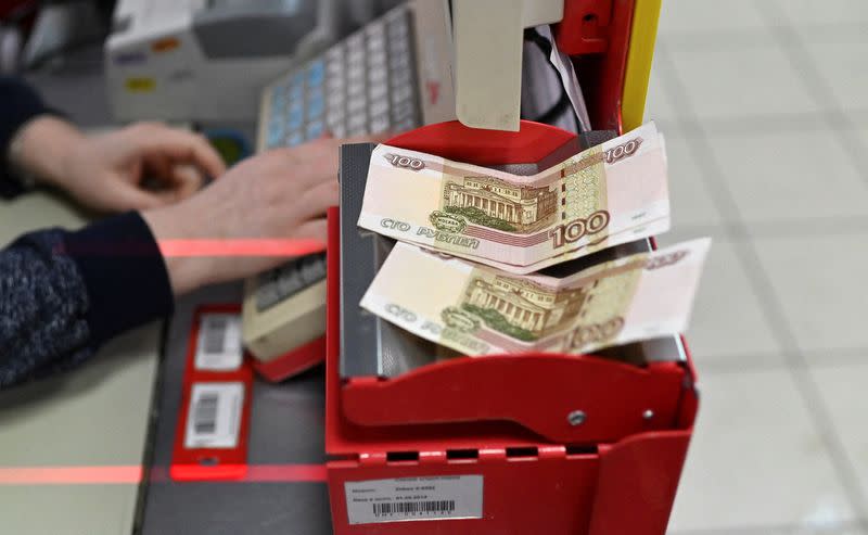 Russian 100-rouble banknotes are placed on a cashier's desk at a supermarket in Tara