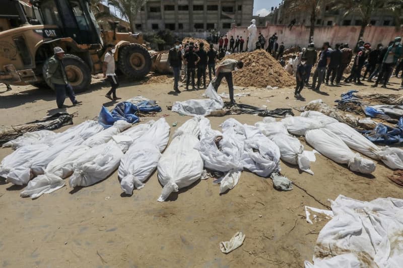 Palestinian health workers recover bodies of Palestinians buried in Nasser Hospital compound, after the Israeli Defense Forces (IDF) withdrew from the area in Khan Yunis, southern Gaza Strip. he UN Security Council on Friday called for an investigation into mass graves discovered near health facilities in the Gaza Strip. Omar Naaman/dpa