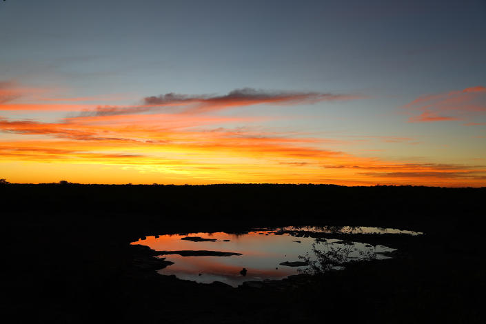 <p>Another dramatic sunset at the Moringa watering hole. It is always worth the price of admission. Sunsets are quiet, with only the sounds of wildlife and cameras clicking. (Photo: Gordon Donovan/Yahoo News) </p>