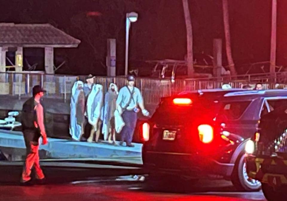 Miami-Dade County Fire Rescue medics escort several people down a dock at Black Point Marina Sunday night, Sept. 4, 2022. They just arrived on a fire rescue boat following a vessel crash earlier that evening in which several people were seriously injured.