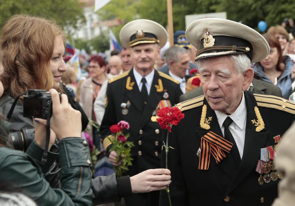 A woman greets a WWII veteran after a Victory Day military parade in Sevastopol, Crimea, Friday, May 9, 2014. Crimea, which hosts a major Russian Black Sea Fleet base, is also set to hold a massive navy parade in the port of Sevastopol, celebrating the Russian takeover. (AP Photo/Ivan Sekretarev)