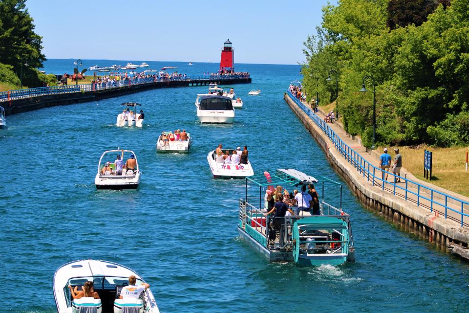 The height of summer fun: Boaters and the new commercial paddle barge, Charlevoix Cycle Pub, (far right) cruise through Charlevoix's Pine River Channel into Lake Michigan on Saturday,  July 9.