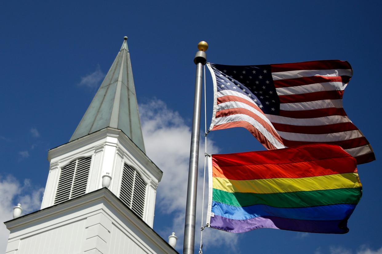 FILE - A gay Pride rainbow flag flies with the U.S. flag in front of the Asbury United Methodist Church in Prairie Village, Kan., on Friday, April 19, 2019. As of June 2023, more than 6,000 United Methodist congregations — a fifth of the U.S. total — have now received permission to leave the denomination amid a schism over theology and the role of LGBTQ people in the nation's second-largest Protestant denomination. (AP Photo/Charlie Riedel, File) ORG XMIT: NY487