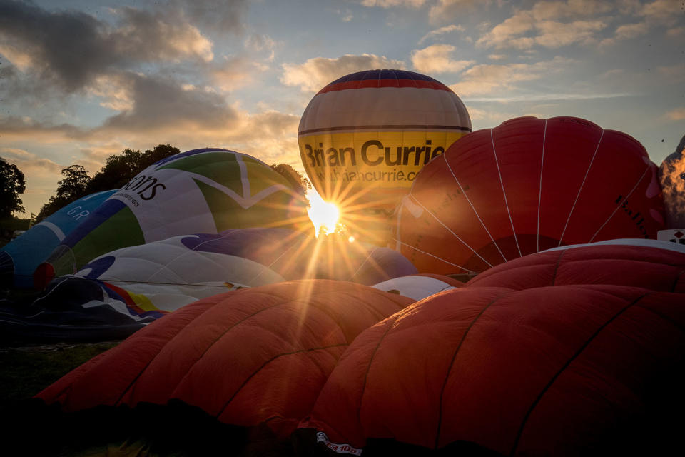 <p>Hot air balloons are inflated and take to the skies as they participate in the mass assent at sunrise in the main arena on the second day of the Bristol International Balloon Fiesta on August 11, 2017 in Bristol, England. (Photo: Matt Cardy/Getty Images) </p>